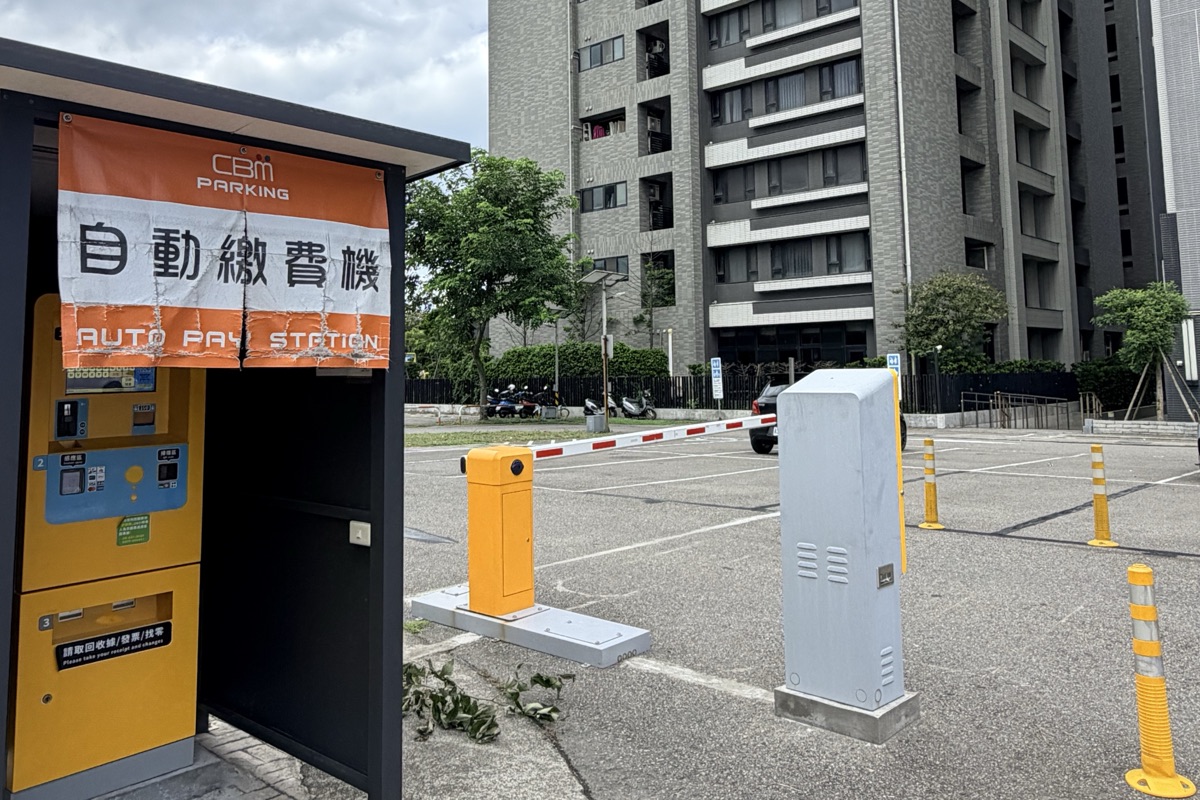 停車場的自動繳費機與出口柵欄，繳費機上方掛有 CBM Parking 自動繳費機布條。