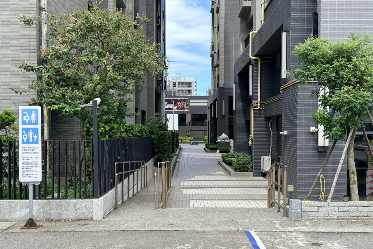 兩棟大樓之間的通道入口，左側設有附扶手的斜坡道，通道盡頭通往中山路。